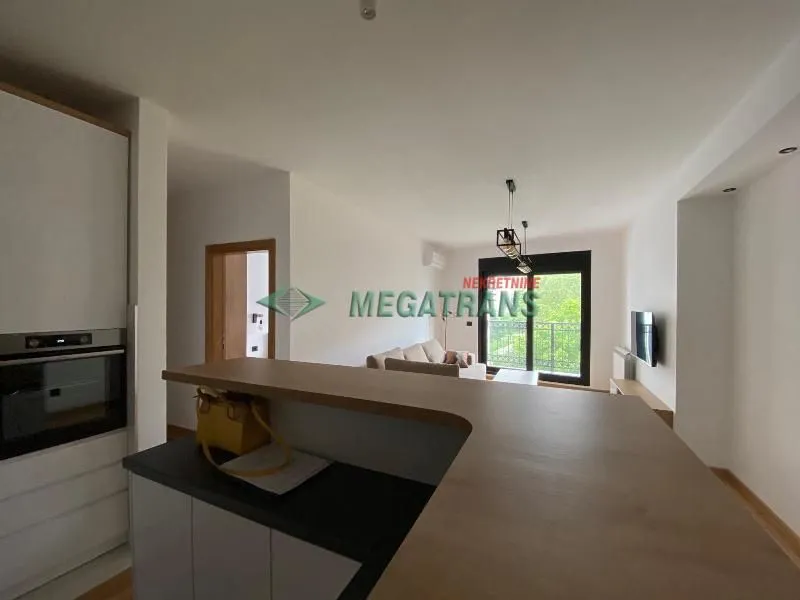 View from the kitchen with a breakfast bar towards the living room and balcony.