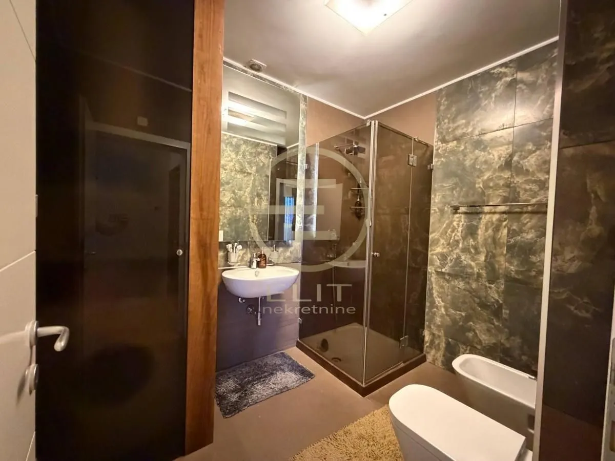 Moderno kupatilo sa tuš kabinom, umivaonikom i sanitarijama.