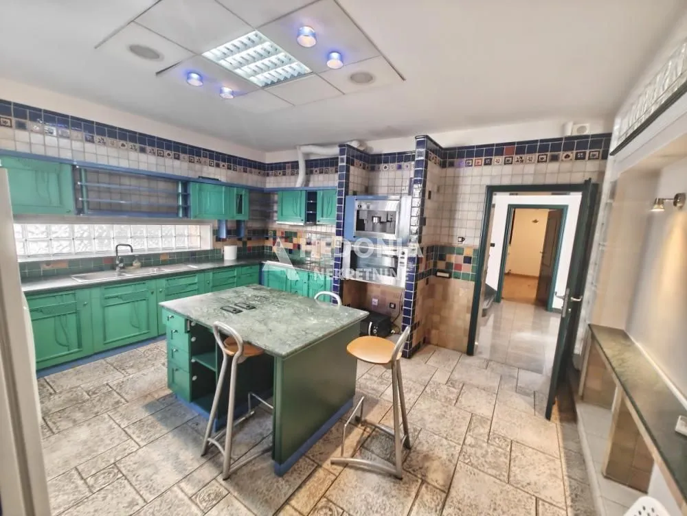 Spacious kitchen with green cabinetry, an island, and built-in appliances.