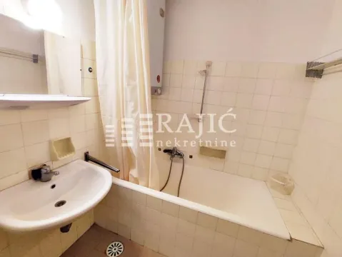 Smaller bathroom with a bathtub, washbasin, and tiled walls. - image 20