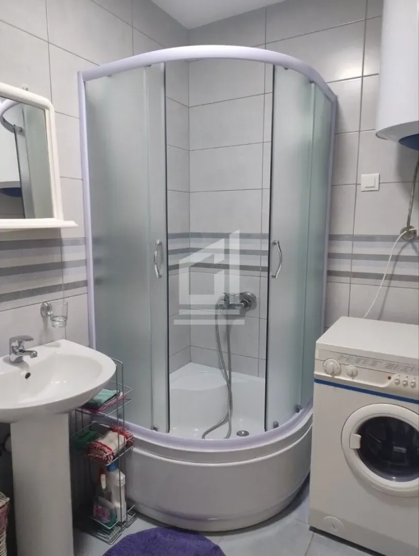 Bathroom with a shower cabin, washbasin, and washing machine.
