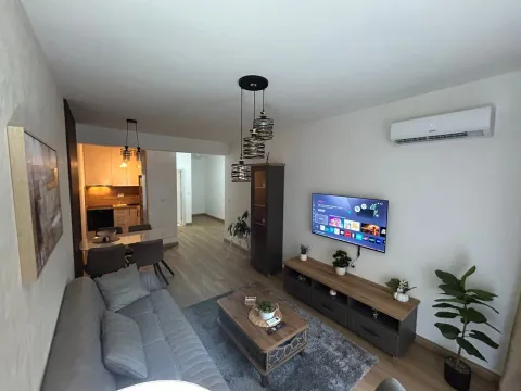 Living room with a sofa, TV, and dining area in the background. - image 2