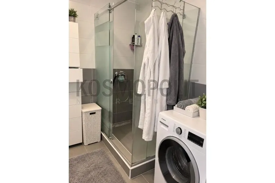 Bathroom with a shower cabin and washing machine.