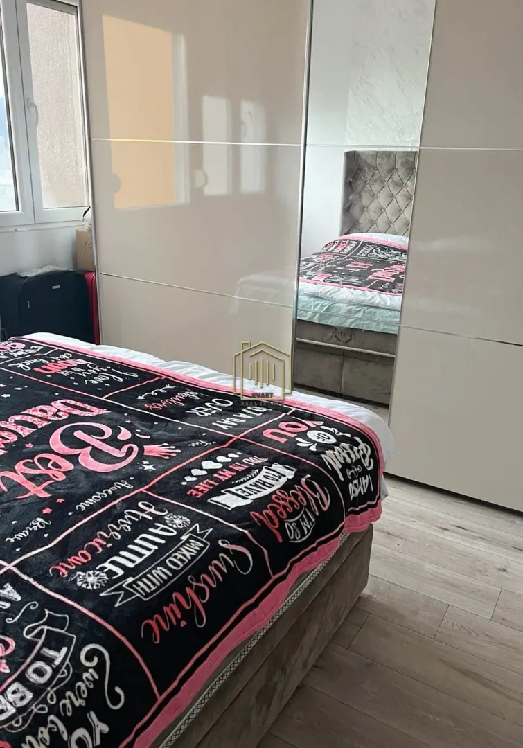 Spavaća soba sa bračnim krevetom i velikim ugradnim plakarom sa ogledalom.
