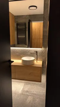View from the hallway into a modernly decorated bathroom with a washbasin and wooden elements. - image 14
