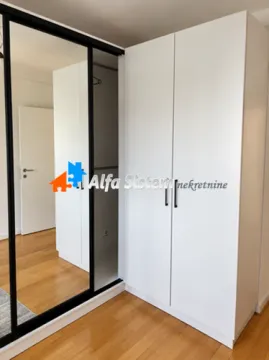 White wardrobe with sliding doors and a mirror in a room with a wooden floor. - image 8