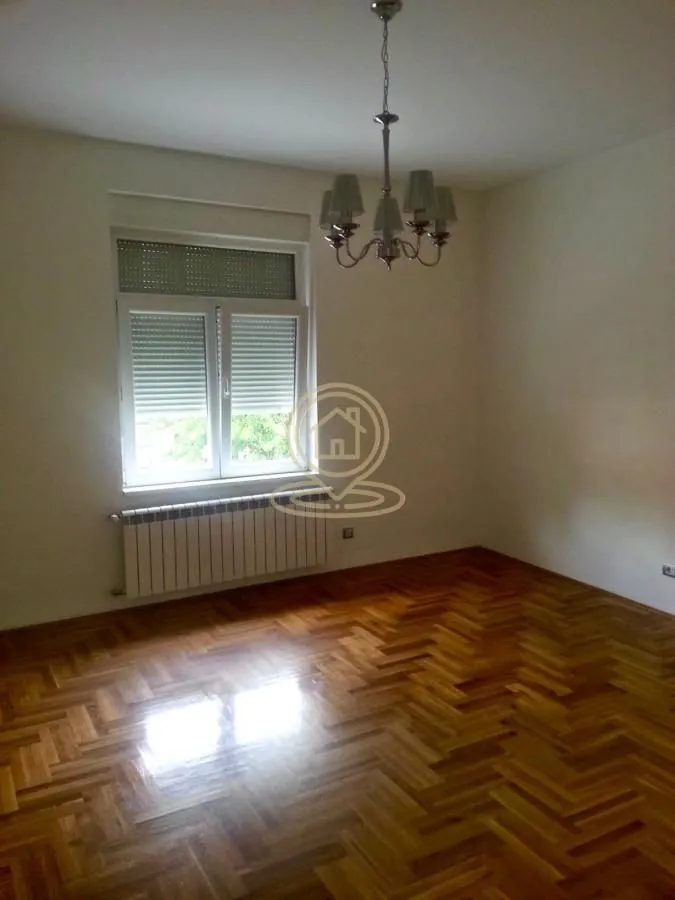 Empty room with hardwood flooring, a window, and a chandelier.