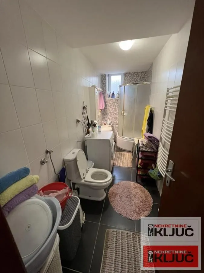 Kupatilo opremljeno sanitarijama, tuš kabinom i mašinom za veš.