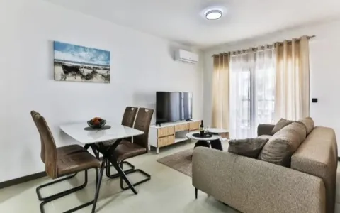 Living room with a sofa, TV, and dining table. - image 4