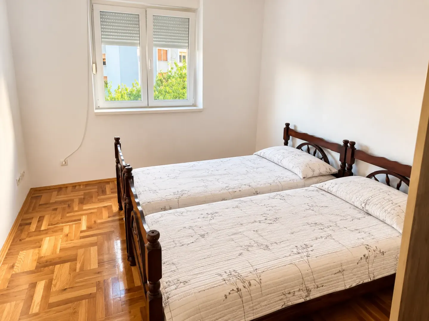 Bedroom with two wooden beds and parquet flooring.