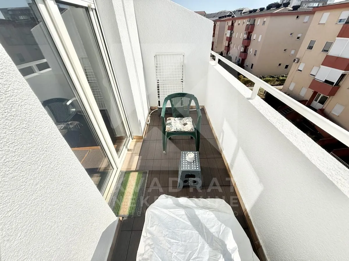 Smaller furnished balcony with glass balcony doors.