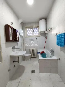 Manje kupatilo obloženo svetlim pločicama sa kadom, lavaboom i toaletom. - image 12