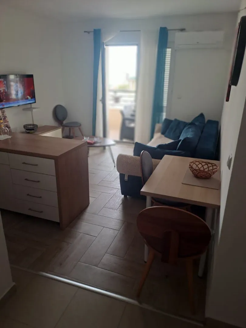 Living room with a sofa, TV, and dining table with chairs.