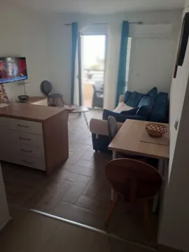 Living room with a sofa, TV, and dining table with chairs. - image 7