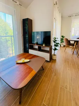 Living room with a wooden coffee table, TV unit, and dining area in the background. - image 15