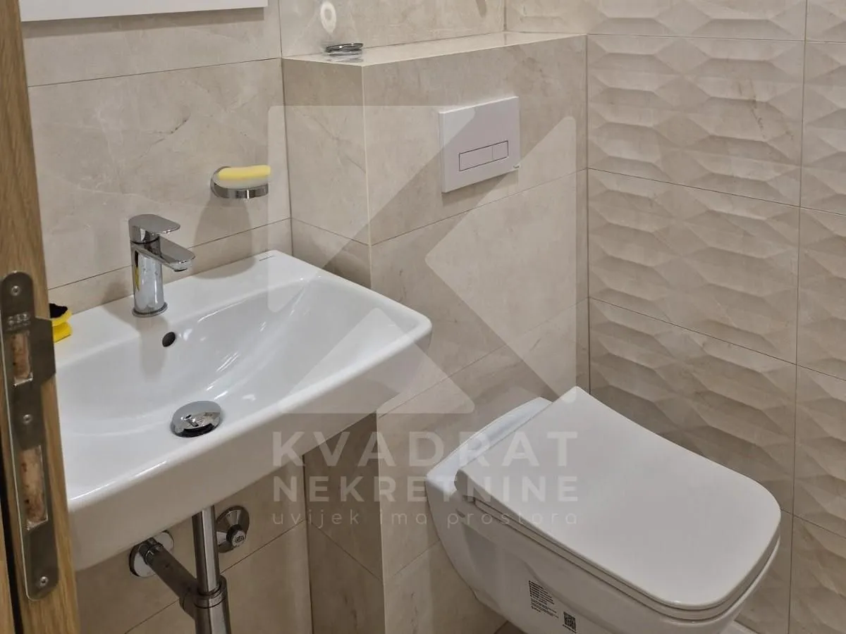 View of the sink and toilet in a bathroom with ceramic tiles.