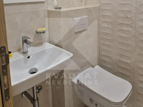 View of the sink and toilet in a bathroom with ceramic tiles. - image 5