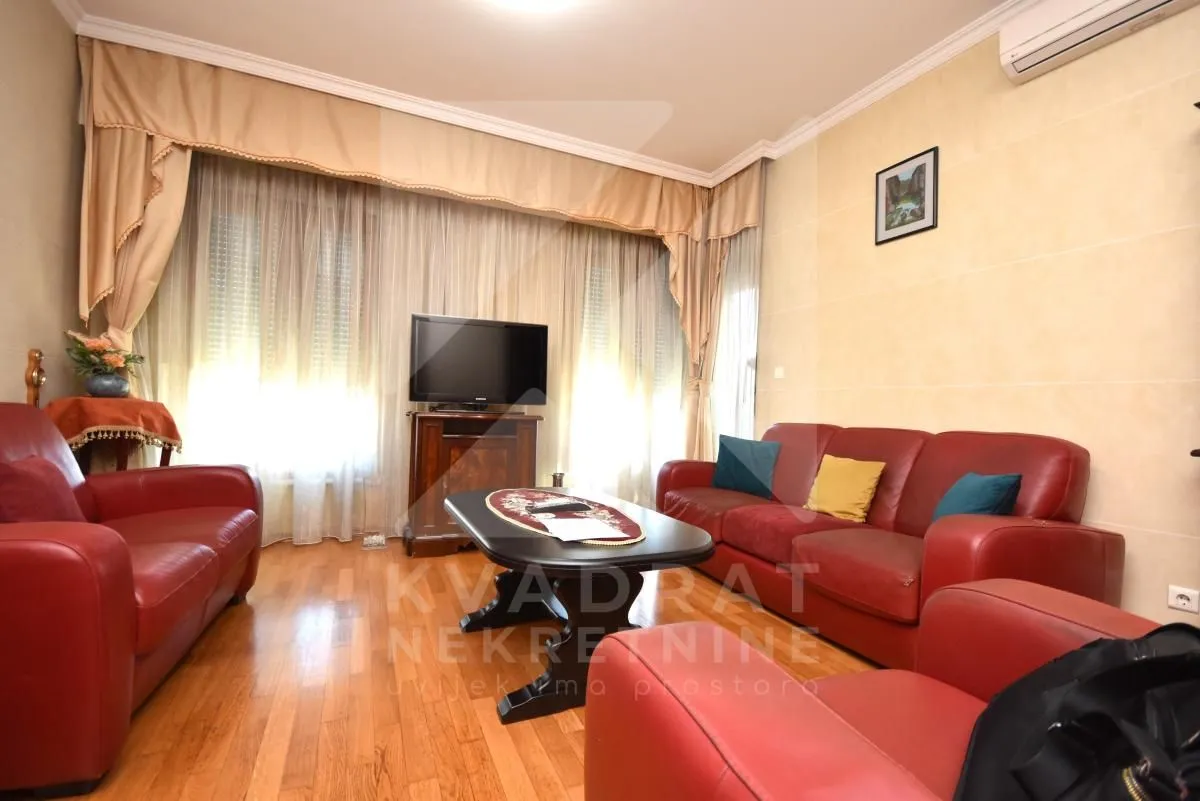 Living room with red leather sofas and a television.