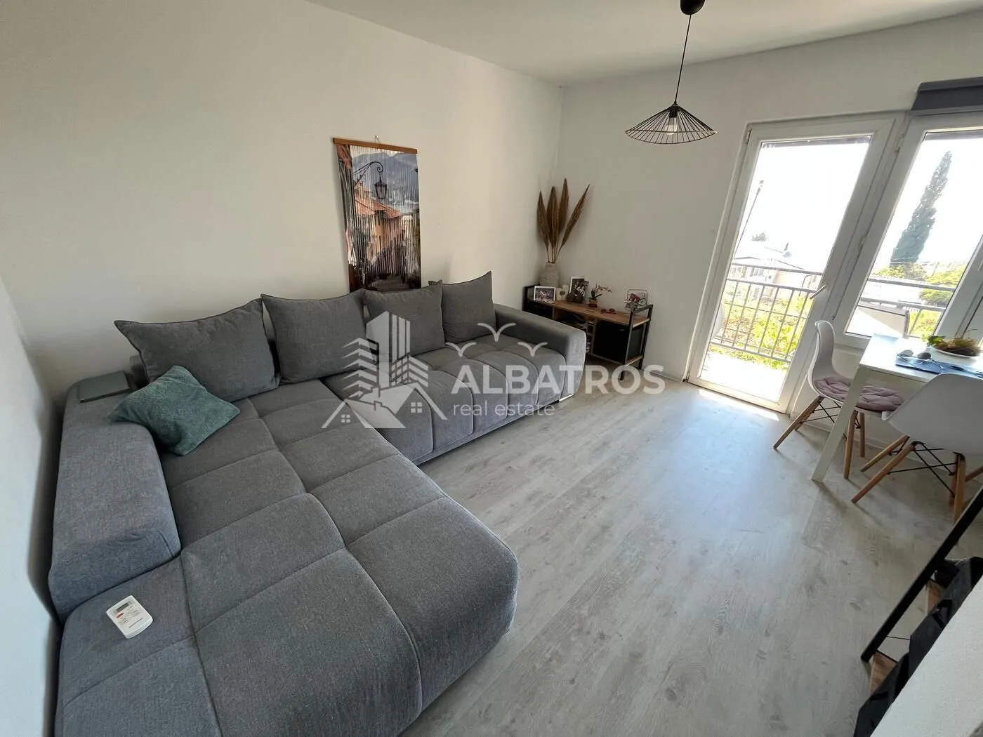 Living room with a large grey sectional sofa and access to the balcony.