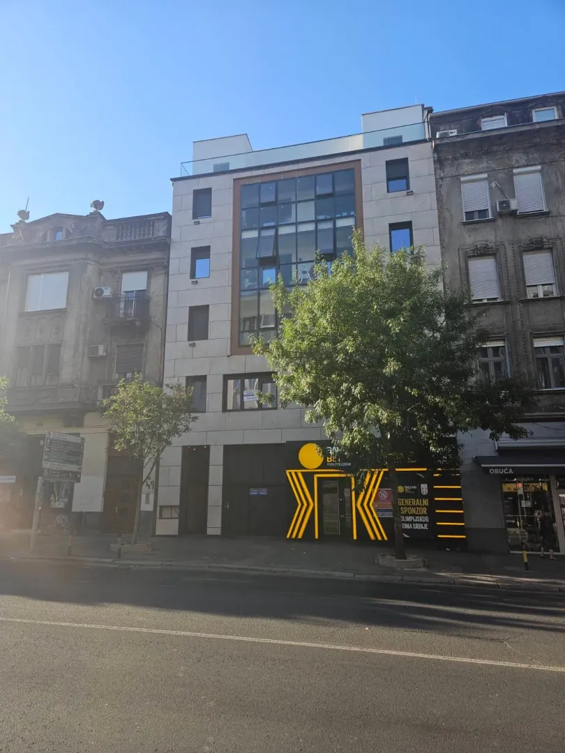 Street view of a modern residential building with commercial space on the ground floor.