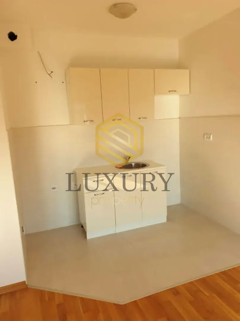 Small kitchen with light-colored cabinets in an empty room.