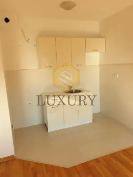 Small kitchen with light-colored cabinets in an empty room. - image 3