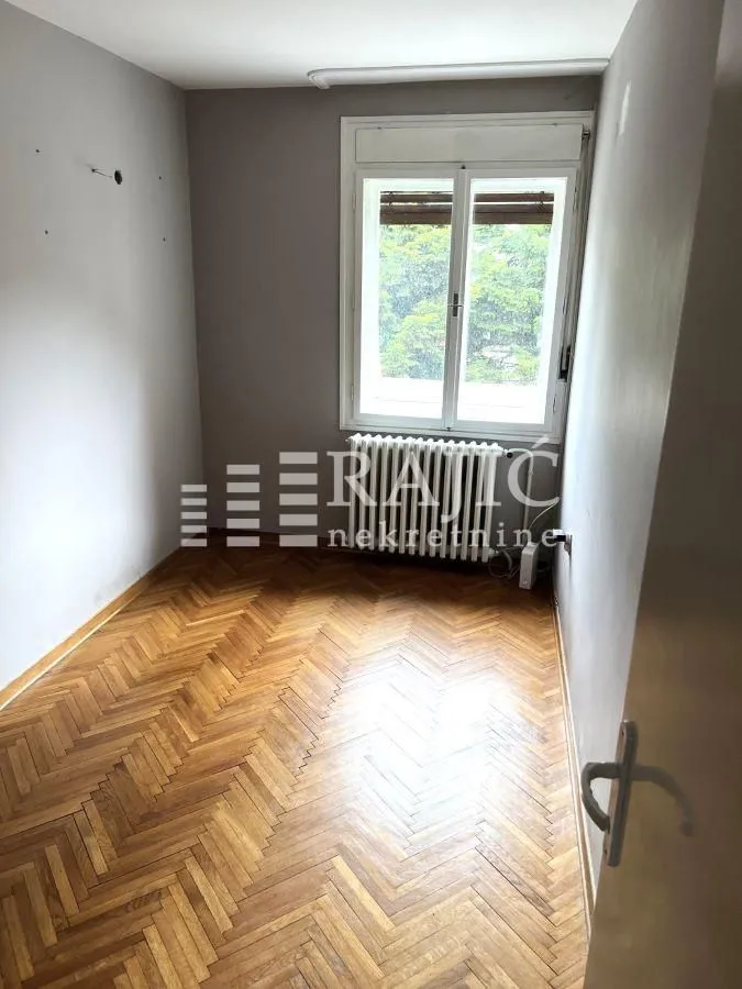 Prazna soba sa parketom i prozorom.
