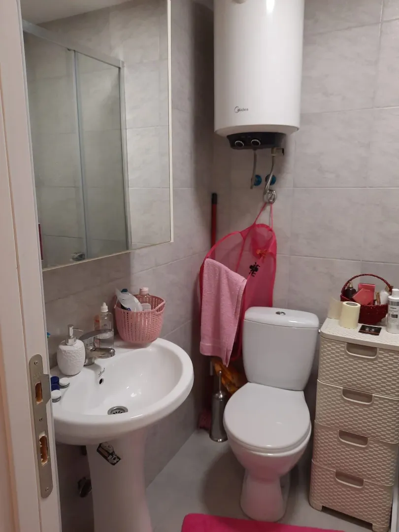 Manje kupatilo sa umivaonikom, WC šoljom, bojlerom i ormarićem.