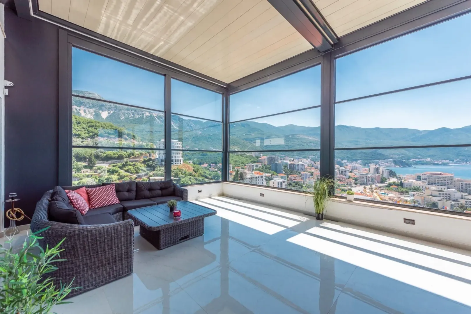 Glazed terrace with lounge seating and a panoramic view of the city and sea.