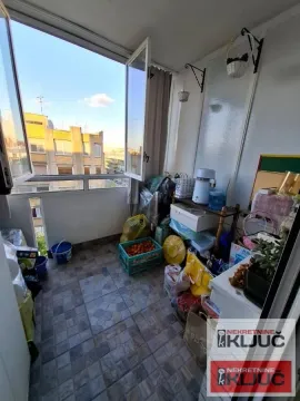 Zastakljeni balkon sa keramičkim pločicama i pogledom na okolne zgrade. - image 15