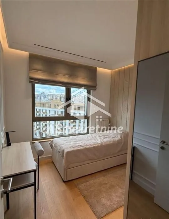 Furnished bedroom with a bed, desk, and a window.