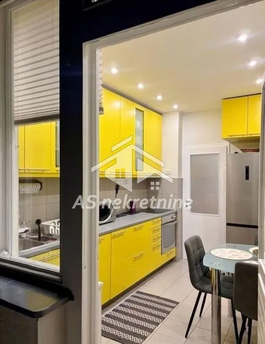 Modern kitchen with yellow units and a dining table.