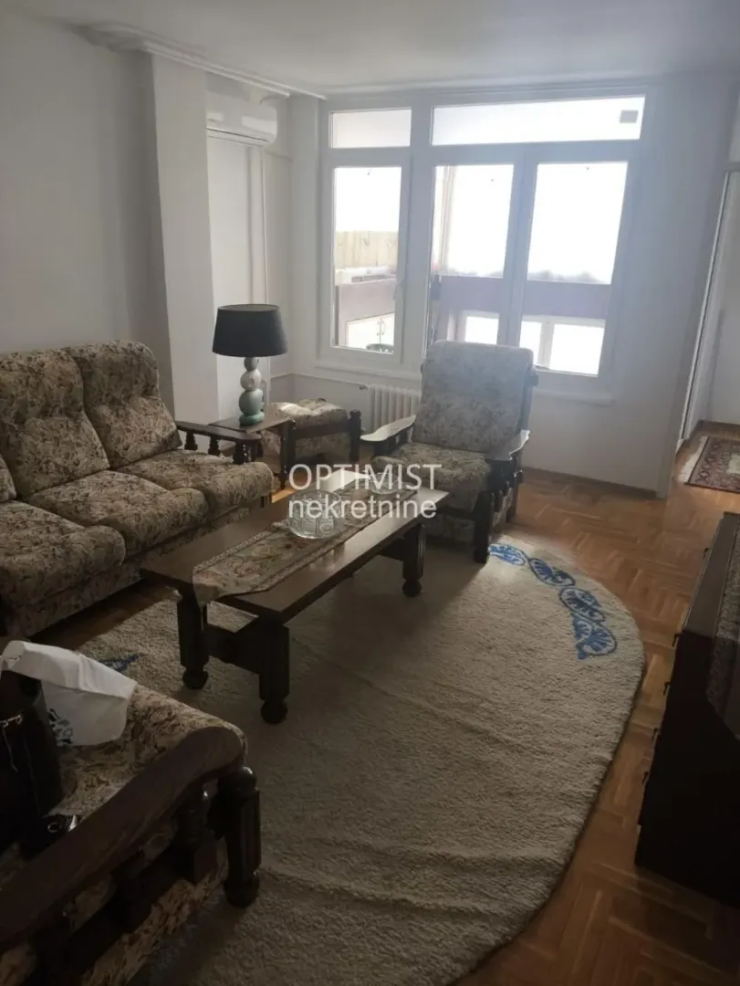 Living room with a seating set and windows looking outside.