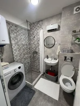 Modern bathroom with a shower cabin, washing machine, and toilet. - image 11
