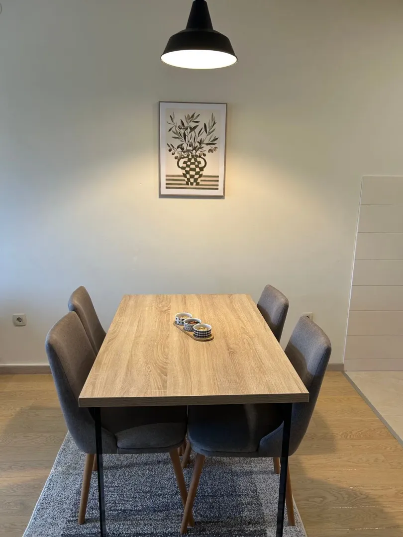 Dining area with a wooden table and four grey chairs.