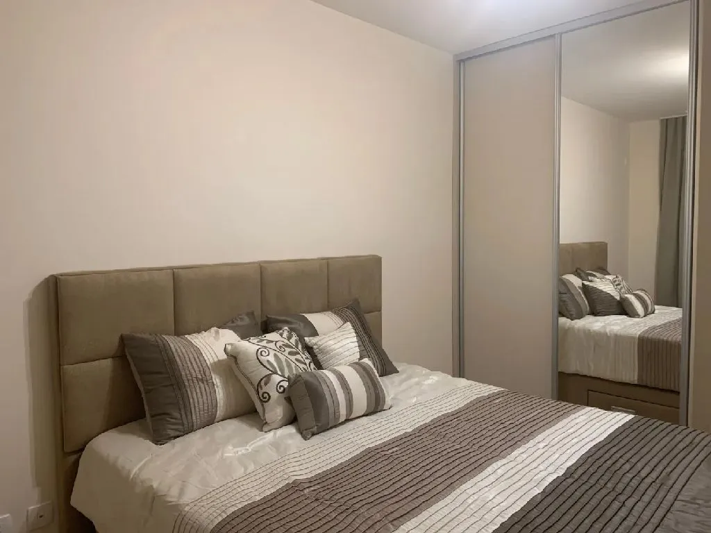 Furnished bedroom with a double bed and a built-in mirrored wardrobe.