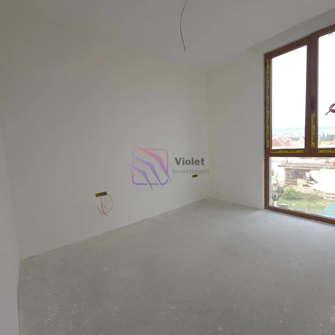 Empty unfinished room with a large window and white walls.