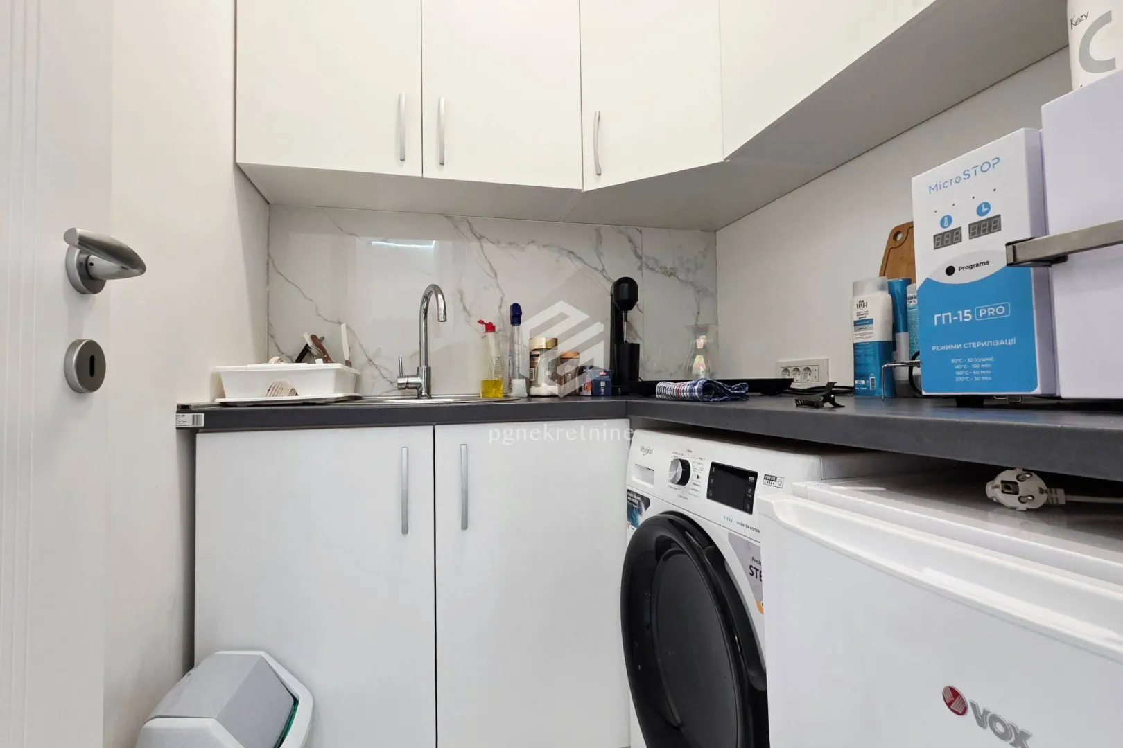 Small kitchen with white cabinets, a sink, and a built-in washing machine.