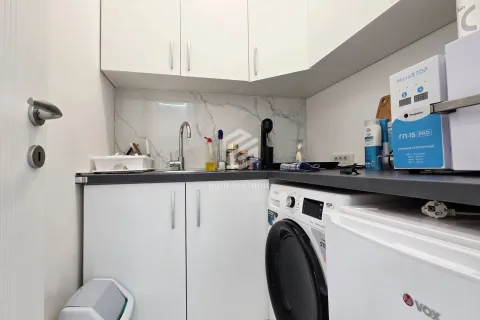 Small kitchen with white cabinets, a sink, and a built-in washing machine. - image 10
