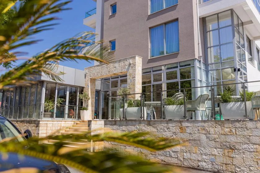 Exterior of a modern residential building with a stone facade and terrace.