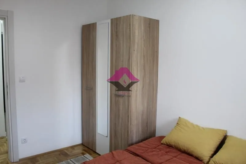 Small bedroom with a bed and a wooden wardrobe.
