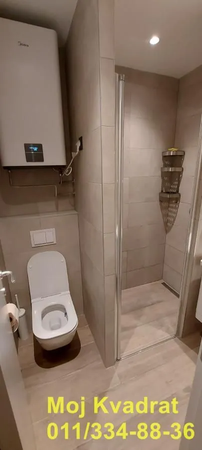 Moderno kupatilo sa tuš kabinom, wc šoljom i bojlerom.