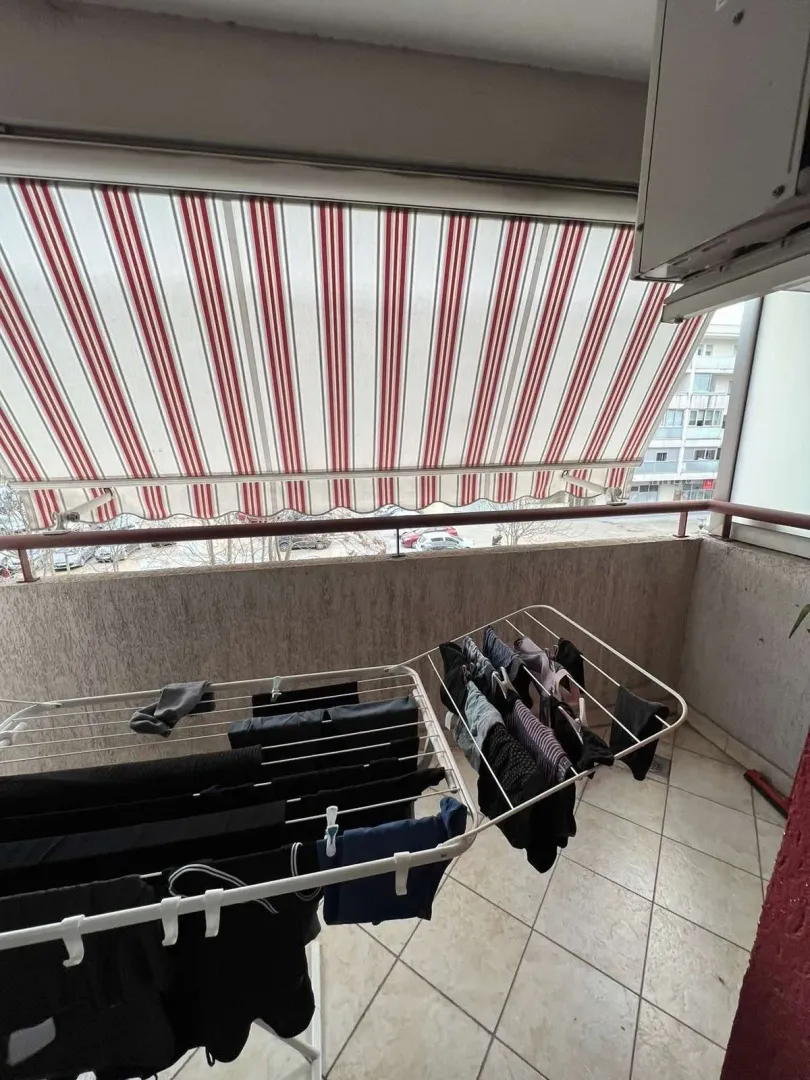 Balkon sa prugastom tendom i sušilicom za veš.