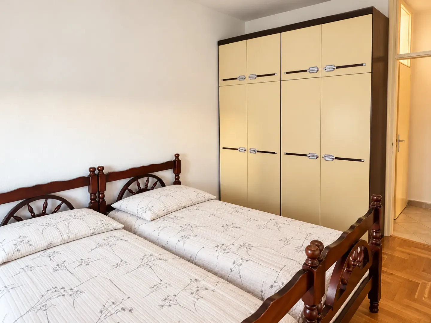 Bedroom with two wooden beds and a large wardrobe.