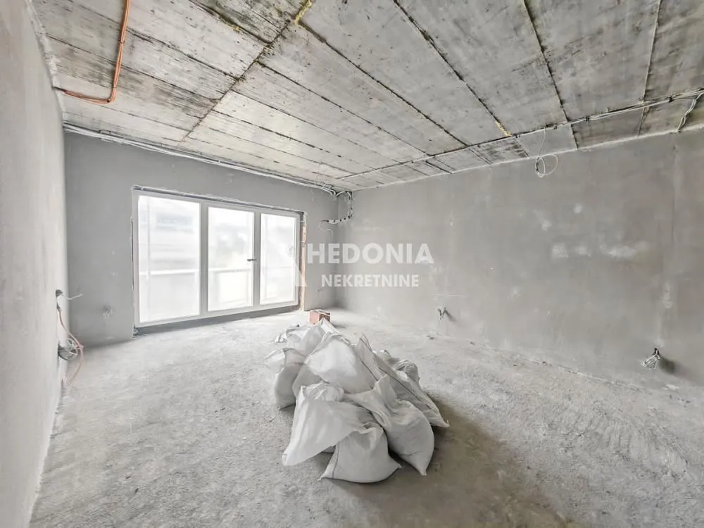 Neopremljena prostorija u grubim radovima sa balkonskim vratima.
