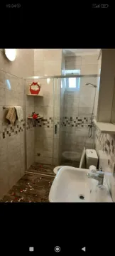 Small bathroom with a walk-in shower, washbasin, and toilet. - image 3