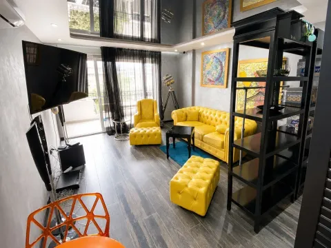 Living room with yellow furniture sets, a shelving unit, and a television. - image 4