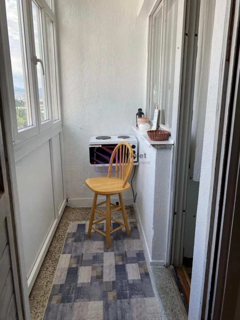 Zastakljeni balkon sa stolicom i malim šporetom.