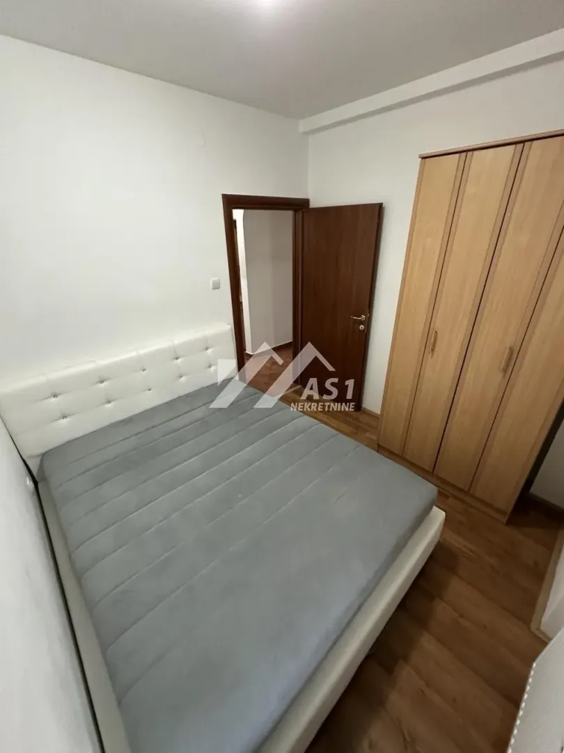 Spavaća soba sa bračnim krevetom i drvenim ormanom.