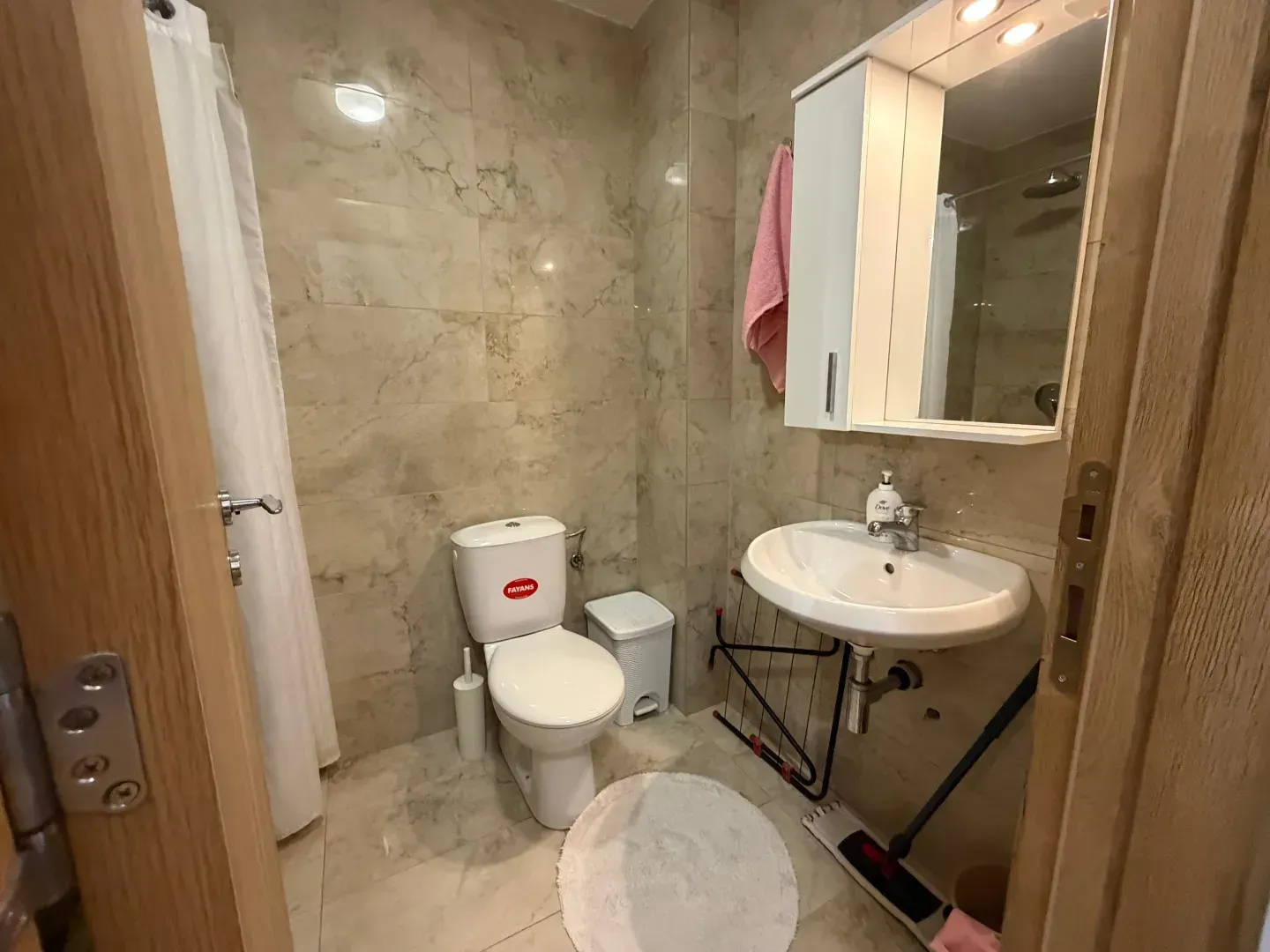 Manje kupatilo obloženo keramičkim pločicama sa umivaonikom i WC šoljom.